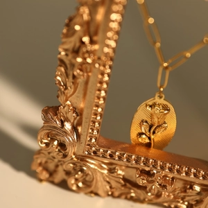 Detail of vintage gold-toned rose embossed oval pendant hanging on an ornate frame