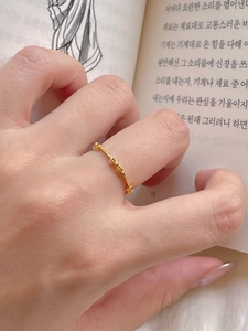 Detail shot of a minimalist gold bow ring with bamboo style texture on a hand