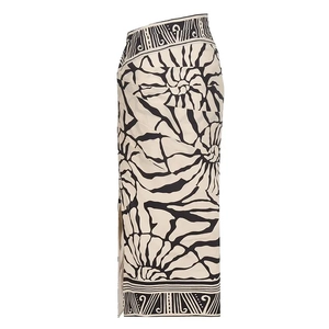 Detail of high-waist printed midi skirt with abstract black floral patterns and side slit