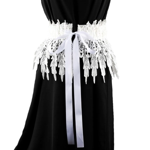 Detailed view of white lace corset belt with ribbon bow tied on black dress