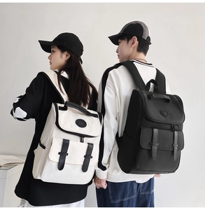 Rear view of couple wearing black and beige nylon backpacks with leather flap buckles
