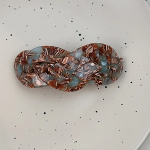 Detailed macro view of French style braided hair clip with blue and brown marble texture