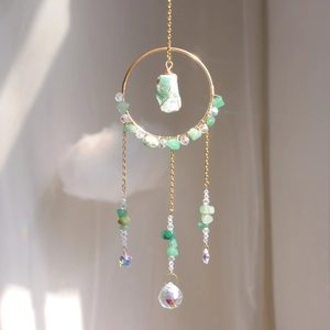 Detailed suncatcher with green stones and crystal prism producing rainbow light spots