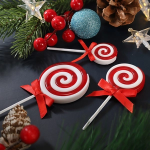 Christmas red and white swirl lollipop decorations with red bows on festive pine background