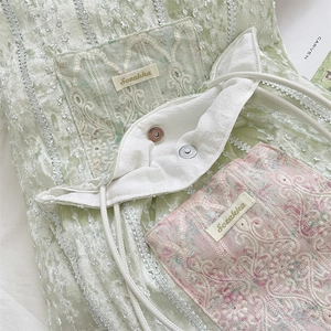 Detail of green velvet bag featuring floral lace patchwork and secure metal buckle