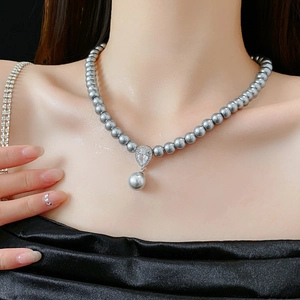 Detail of grey pearl necklace with a zircon waterdrop pendant worn on a model's neck