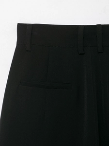 Detailed view of black tailored pants featuring belt loops and precise welt pocket design