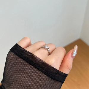 Close-up of a sparkling heart-shaped zircon ring on a hand with elegant sequined nails