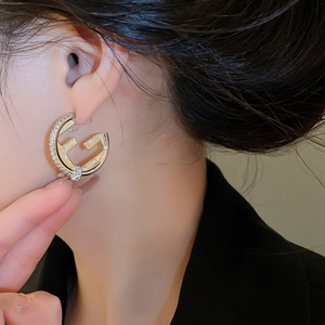 Detail of 18K gold-plated earrings with zircon stones worn by a model in close-up