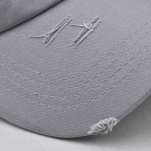 Close-up of distressed gray cotton baseball cap with white 17 embroidery and ripped details