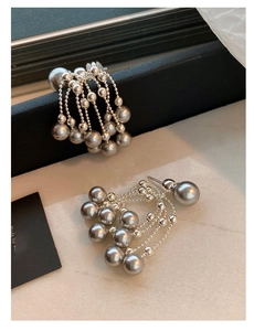 Close-up of elegant French vintage silver needle earrings with grey pearl tassels