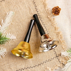 Golden and silver Christmas hand bells with black wooden handles on rustic linen background