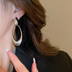 Close-up of a silver-tone hollow oval drop earring on model for high fashion style