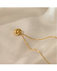 Detailed close-up of 14K gold plated heart necklace with relief pattern on satin background