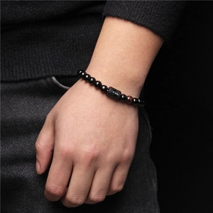 Detail of men's black stone beaded bracelet with Capricorn zodiac symbol on model