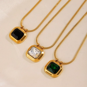 Collane placcate in oro con pendenti quadrati in nero, bianco e verde su sfondo di seta beige