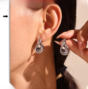 Close-up of minimalist silver multi-loop twisted earrings worn on the ear for detail