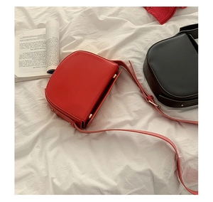 Lifestyle view of vintage red and black PU leather saddle bags on a white surface