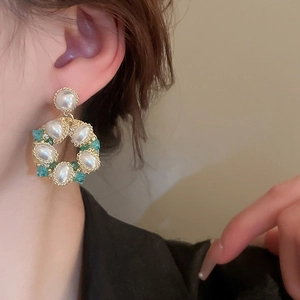 Vintage gold flower earrings with white pearls and green crystal accents on model