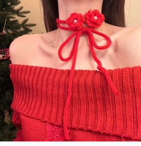 Detail of red handmade knit flower necklace with pearl centers on an adjustable cord