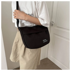 Detailed view of black nylon shoulder bag with signature brand label on a model