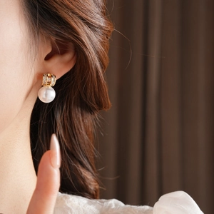 Close-up of gold-plated pearl drop earrings with diamond studs on a model's ear