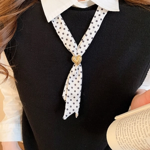 Detail of vintage polka dot silk scarf necklace with a golden heart-shaped metal buckle