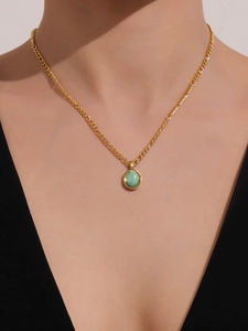Detailed view of a gold chain necklace featuring a round green turquoise stone on a model