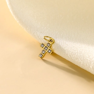 Detail shot of a gold-plated cross pendant with micro-pave zircons on silk fabric