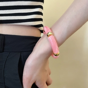 Close-up of pink marbled acrylic tubular bead bracelet with gold metal spacers on wrist