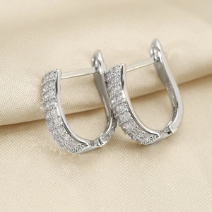 Elegant silver U-shaped hoop earrings with pave-set crystals on champagne silk background