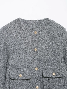 Detail of grey textured jacket showing golden embossed buttons and flap pockets