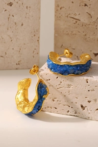 Detail of PVD gold plated C-shape earrings with crushed blue stones on stone texture