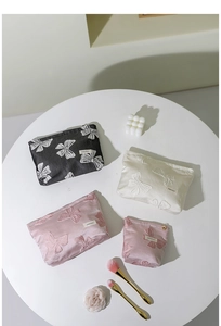 Vista piatta di borse per trucco vintage in rosa, crema e nero con motivi a farfalla