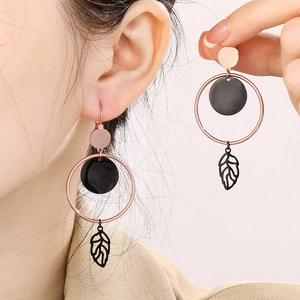 Rose gold circle earrings with black round disc and leaf pendant on model