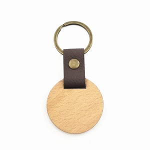 Detailed shot of light wood keychain with dark brown leather strap and bronze metal ring