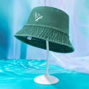 Close-up of a dark green washed bucket hat featuring a white skeleton skateboard embroidery