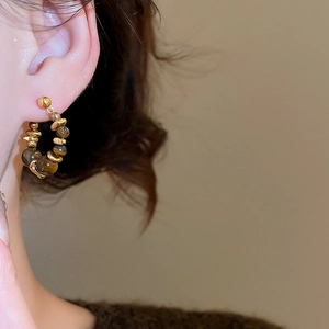 Close-up of vintage style stainless steel hoop earrings with tiger eye stone beads on model