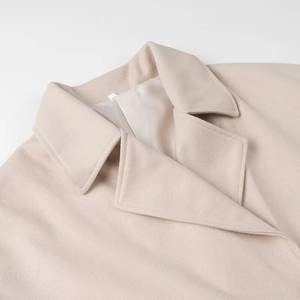 Close-up of lapel collar on light beige double-breasted short wool coat with soft texture