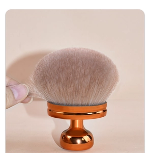 Close-up of soft pink bristles on a large mushroom makeup brush with orange metal base