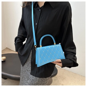 Detail of blue quilted handbag with star patterns, gold studs and woven top handle