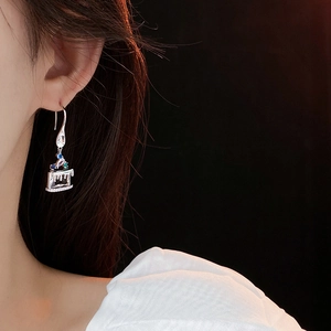 Detail of asymmetrical cupcake earrings with colorful zircon stones worn on the ear