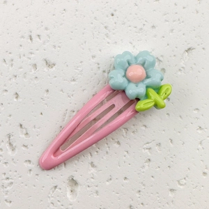 Detail of pink metal BB hair clip with light blue resin flower and green leaf ornament