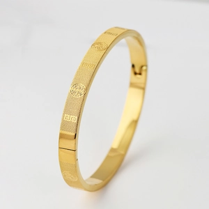 Detailed view of gold stainless steel bangle featuring grid texture and religious relief