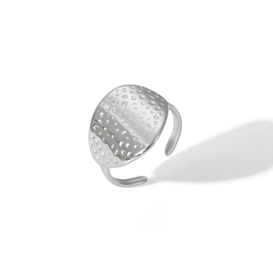Macro shot of silver adjustable open ring with hammered oval texture on stainless steel