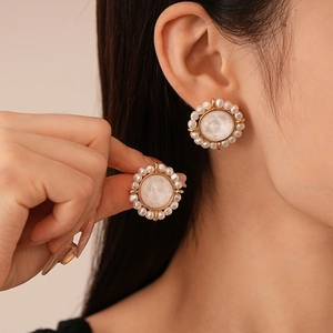 Detailed close-up of vintage round pearl flower earrings with gold metal base on model