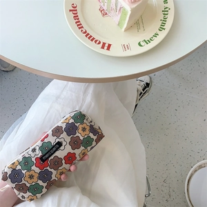 Floral canvas pencil case with zipper closure shown in a lifestyle tabletop setting