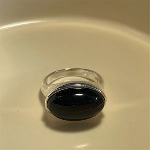 Close-up of 925 sterling silver ring with oval black gemstone on a beige plate