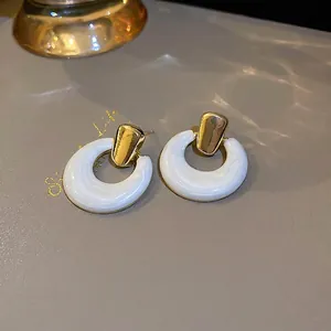 Detail view of retro white resin hoop earrings with elegant gold metal studs and water patterns