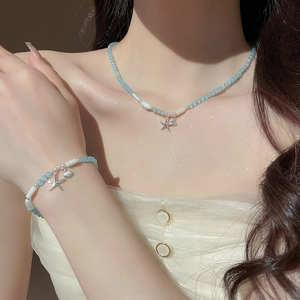 Détail d'un ensemble collier et bracelet en pierre œil de chat bleu clair avec étoiles de mer